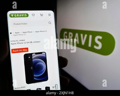 Stuttgart, Allemagne, 01-21-2023 : personne tenant un téléphone portable avec la page web de Gravis Computervertriebsgesellschaft mbH sur l'écran devant le logo. Mise au point Banque D'Images