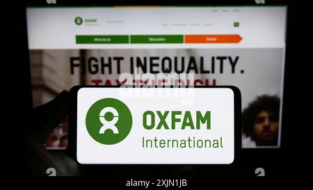 Stuttgart, Allemagne, 01-21-2023 : personne tenant un smartphone avec le logo de la confédération Oxfam International sur l'écran devant le site web. Concentrez-vous sur Banque D'Images