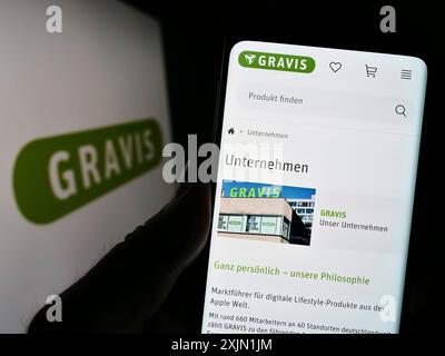 Stuttgart, Allemagne, 01-21-2023 : personne tenant un téléphone portable avec le site web de Gravis Computervertriebsgesellschaft mbH sur l'écran avec logo. Concentrez-vous sur Banque D'Images