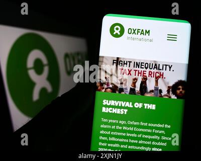 Stuttgart, Allemagne, 01-21-2023 : personne tenant un smartphone avec le site web de la confédération Oxfam International sur l'écran devant le logo. Concentrez-vous sur Banque D'Images