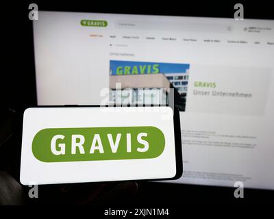 Stuttgart, Allemagne, 01-21-2023 : personne tenant un téléphone portable avec le logo de Gravis Computervertriebsgesellschaft mbH sur l'écran devant la page web. Banque D'Images