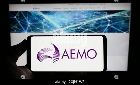 Stuttgart, Allemagne, 01-27-2023, personne tenant un téléphone portable avec le logo de l'Australian Energy Market Operator (AEMO) sur l'écran en face de la page Web. Mise au point Banque D'Images