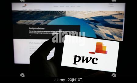 Stuttgart, Allemagne, 01-25-2023, personne tenant un smartphone avec le logo de la société de conseil PricewaterhouseCoopers (PWC) sur l'écran devant le site Web. Banque D'Images