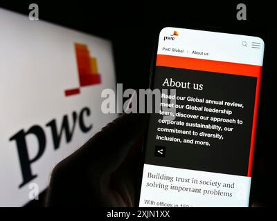 Stuttgart, Allemagne, 01-25-2023, personne tenant un smartphone avec le site web de la société de conseil PricewaterhouseCoopers (PWC) sur l'écran avec logo. Mise au point Banque D'Images