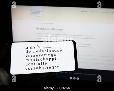 Stuttgart, Allemagne, 01-29-2023, personne tenant un téléphone portable avec le logo de la compagnie d'assurance néerlandaise ASR Nederland NV sur l'écran devant l'entreprise Banque D'Images