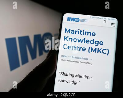 Stuttgart, Allemagne, 03-07-2023 : personne tenant un téléphone portable avec la page web de l'Organisation maritime internationale (OMI) sur l'écran devant le logo. Mise au point Banque D'Images