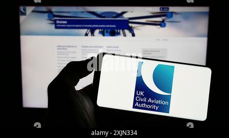 Stuttgart, Allemagne, 03-12-2023 : personne tenant un téléphone portable avec le logo de l'autorité de régulation britannique de l'aviation civile (CAA) sur l'écran devant la page Web. Banque D'Images