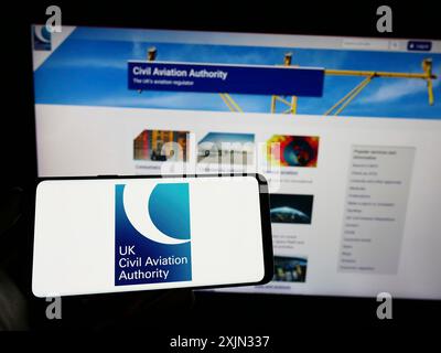 Stuttgart, Allemagne, 03-12-2023 : personne tenant un téléphone portable avec le logo de l'autorité de régulation britannique de l'aviation civile (CAA) sur l'écran devant la page Web. Banque D'Images