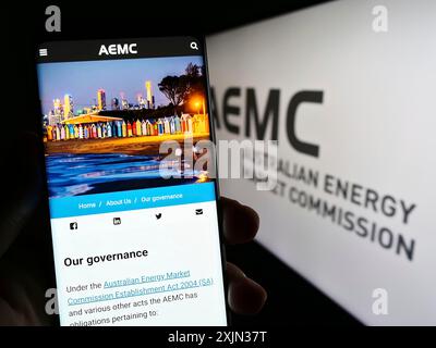 Stuttgart, Allemagne, 03-13-2023 : personne tenant un téléphone portable avec le site de la Commission australienne du marché de l'énergie (AEMC) sur l'écran devant le logo. Mise au point Banque D'Images