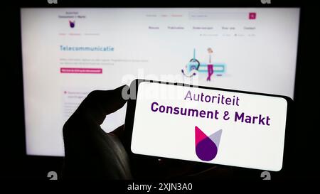 Stuttgart, Allemagne, 03-12-2023 : personne tenant un téléphone portable avec le logo du régulateur néerlandais Autoriteit Consument en Markt (ACM) sur l'écran devant Banque D'Images