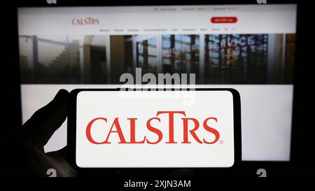 Stuttgart, Allemagne, 03-14-2023 : personne tenant un smartphone avec le logo du California State Teachers Retirement System (CalSTRS) sur l'écran avec une page web. Banque D'Images