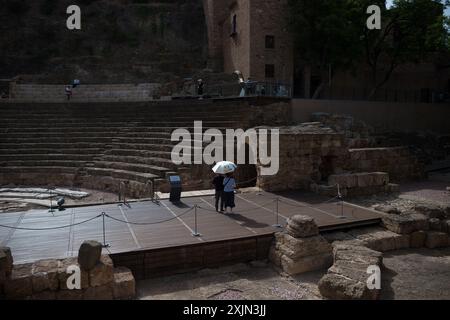 Malaga, Espagne. 19 juillet 2024. Un couple de touristes sont vus utiliser un parapluie pour se protéger du soleil lorsqu'ils visitent l'amphithéâtre romain pendant la première canicule espagnole de l'été. L’Agence d’État météorologique espagnole a émis un avertissement orange pour plusieurs villes du pays, en raison de la combinaison de températures élevées, de poussière et de brume provenant d’Afrique du Nord qui feront monter les températures au-dessus de 40 degrés. (Photo de Jesus Merida/SOPA images/SIPA USA) crédit : SIPA USA/Alamy Live News Banque D'Images