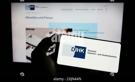 Stuttgart, Allemagne, 03-24-2023 : personne tenant un téléphone portable avec le logo de Deutsche industrie- und Handelskammer (DIHK) sur l'écran devant la page web. Banque D'Images