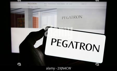 Stuttgart, Allemagne, 04-01-2023 : personne tenant un téléphone portable avec le logo de la société taïwanaise Pegatron Corporation sur l'écran en face de la page Web de l'entreprise. Banque D'Images