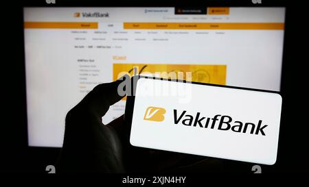 Stuttgart, Allemagne, 04-02-2023 : personne tenant un téléphone portable avec le logo de Turkiye Vakiflar Bankasi TAO (Vakifbank) sur l'écran devant le web d'affaires Banque D'Images