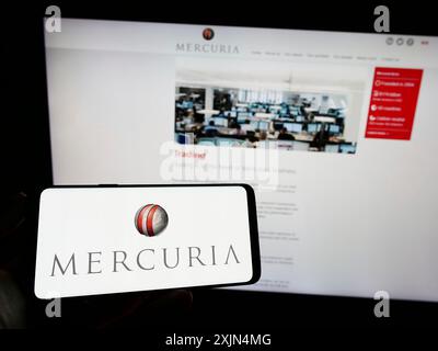 Stuttgart, Allemagne, 04-02-2023 : personne tenant un téléphone portable avec le logo de la société de négoce de marchandises Mercuria Energy Group sur l'écran en face de la page Web. Banque D'Images
