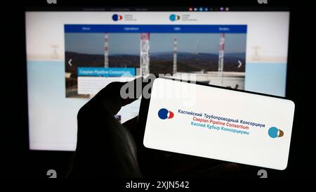 Stuttgart, Allemagne, 04-25-2023, personne tenant un téléphone portable avec le logo du Caspian Pipeline Consortium (CPC) sur l'écran devant la page Web de l'entreprise. Mise au point Banque D'Images