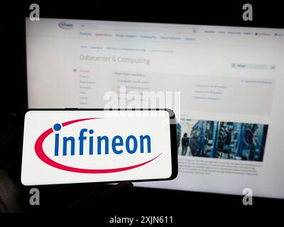 Stuttgart, Allemagne, 04-16-2023 : personne tenant un smartphone avec le logo de la société de semi-conducteurs Infineon technologies AG sur l'écran devant le site Web. Banque D'Images