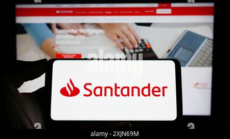 Stuttgart, Allemagne, 04-16-2023 : personne tenant un téléphone portable avec le logo de la société bancaire espagnole Banco Santander sa sur l'écran devant l'entreprise Banque D'Images