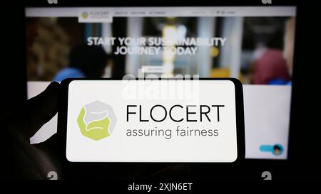 Stuttgart, Allemagne, 03-25-2023, personne tenant un smartphone avec le logo de l'institution de certification de produits FLOCERT GmbH sur l'écran devant le site Web. Banque D'Images