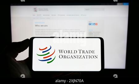 Stuttgart, Allemagne, 03-25-2023, personne tenant un téléphone portable avec le logo de l'Organisation mondiale du commerce (OMC) sur l'écran devant la page Web. Concentrez-vous sur le téléphone Banque D'Images