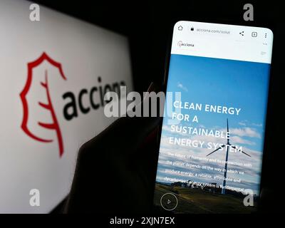 Stuttgart, Allemagne, 04-16-2023 : personne tenant un téléphone portable avec la page web de la société espagnole d'infrastructure Acciona sa sur l'écran devant le logo. Mise au point Banque D'Images