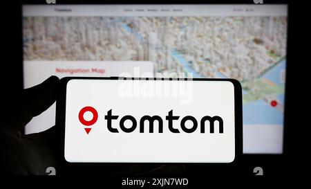 Stuttgart, Allemagne, 06-17-2023 : personne tenant un smartphone avec le logo de la société néerlandaise de technologie de localisation TomTom N.V. sur l'écran devant le site Web. Banque D'Images