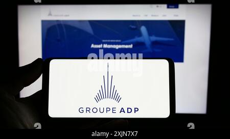 Stuttgart, Allemagne, 06-17-2023 : personne tenant un smartphone avec le logo de l'opérateur aéroportuaire français Groupe ADP sur l'écran devant le site. Banque D'Images