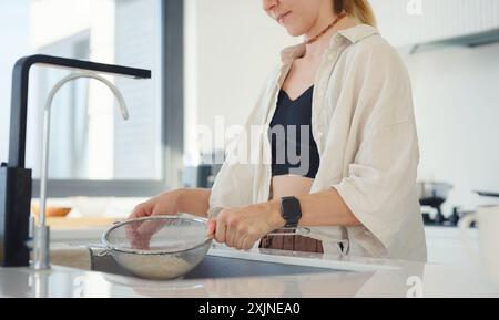 Portrait d'une belle jeune femme faisant la vaisselle, travail à domicile dans une cuisine moderne blanche Banque D'Images