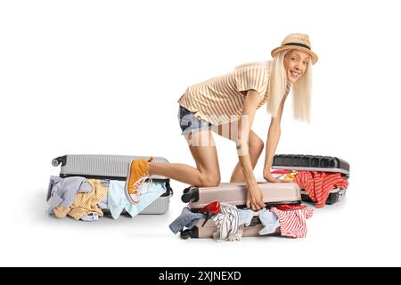 Jeune femme joyeuse essayant de fermer la valise surchargée isolée sur fond blanc Banque D'Images