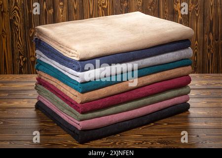 Pile colorée de rouleaux de tissu sur une surface en bois, présentant une variété de textures et de couleurs Banque D'Images