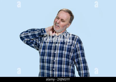 Un homme caucasien mature a une douleur au cou. Isolé sur fond bleu pâle. Banque D'Images