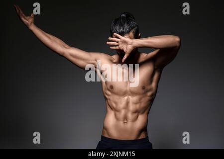 Homme musclé posant le bras levé, mettant en valeur la forme physique et la force. Banque D'Images