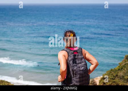 Femme mature sportive profitant de la vue de la falaise à la mer pendant la randonnée sur le sentier de trekking le long de la côte de l'Algarve au Portugal. Vacances d'été actives Banque D'Images