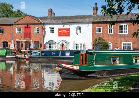 Bateau étroit quittant le canal Trent and Mersey canal à Fradley Junction Staffordshire, pour rejoindre le canal de Coventry par la maison publique Swan inn Banque D'Images