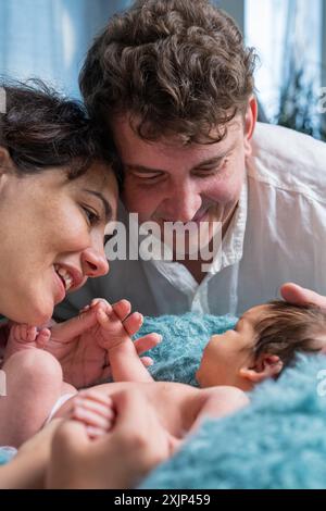 Famille heureuse avec un nouveau-né. Une mère et un père amoureux tiennent doucement leur bébé fils dans leurs bras et regardent tendrement l'enfant. Banque D'Images