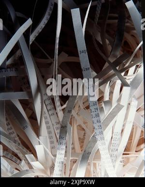 Une image en gros plan d'une pile de papier déchiqueté, révélant des bandes de papier blanc avec des chiffres visibles et des mots imprimés dessus. Le papier déchiqueté est il Banque D'Images