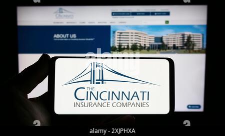 Stuttgart, Allemagne : 06-25-2023 : personne tenant un smartphone avec le logo de la société américaine Cincinnati Financial Corporation sur l'écran devant le site. Banque D'Images