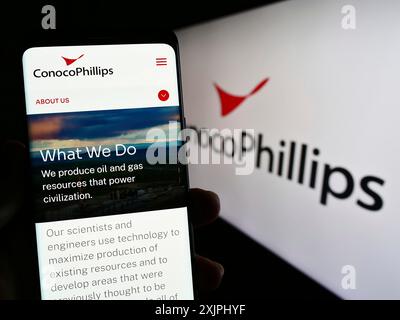 Stuttgart, Allemagne, 06-25-2023, personne tenant un smartphone avec la page web de l'entreprise pétrolière et gazière américaine ConocoPhillips Company sur l'écran avec le logo. Mise au point Banque D'Images