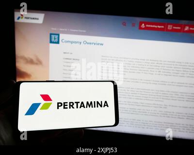 Stuttgart, Allemagne, 06-30-2023, personne tenant un smartphone avec le logo de la société indonésienne PT Pertamina (Persero) sur l'écran devant le site. Mise au point Banque D'Images