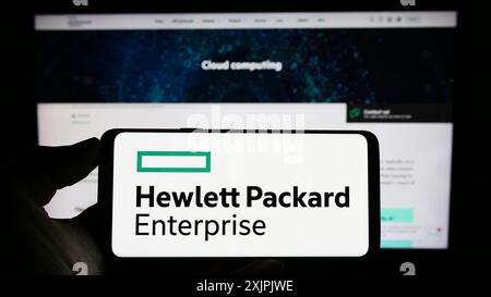 Stuttgart, Allemagne, 07-02-2023 : personne tenant un téléphone portable avec le logo de Hewlett Packard Enterprise Company (HPE) sur l'écran devant l'entreprise Banque D'Images