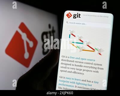 Stuttgart, Allemagne, 07-09-2023 : personne tenant le téléphone portable avec la page Web du système de contrôle de version distribué Git sur l'écran devant le logo. Concentrez-vous sur Banque D'Images