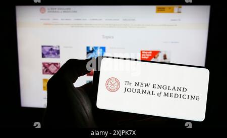 Stuttgart, Allemagne, 07-09-2023 : personne tenant un téléphone portable avec le logo du New England Journal of Medicine (NEJM) sur l'écran devant la page web. Mise au point Banque D'Images