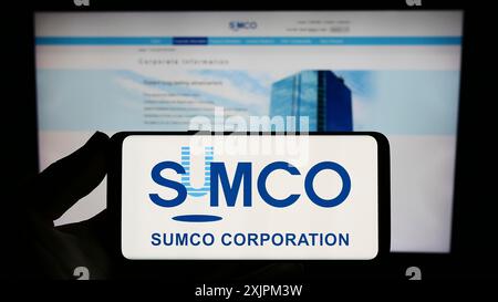 Stuttgart, Allemagne, 07-21-07 2023 : personne tenant un smartphone avec le logo de la société japonaise de semi-conducteurs SUMCO Corporation sur l'écran devant Banque D'Images