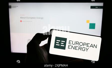 Stuttgart, Allemagne, 07-27-2023, personne tenant un téléphone portable avec le logo de la société danoise European Energy COMME sur l'écran en face de la page web. Banque D'Images