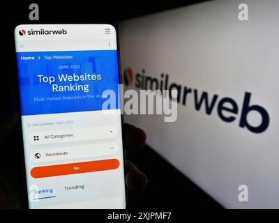 Stuttgart, Allemagne, 07-27-2023, personne tenant un smartphone avec la page Web de la société israélienne d'analyse Web SimilarWeb Ltd sur l'écran avec le logo. Mise au point Banque D'Images