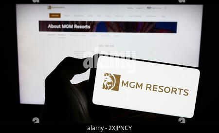 Stuttgart, Allemagne, 08-04-2023 : personne tenant un smartphone avec le logo de la société hôtelière MGM Resorts International sur l'écran devant le site Web. Banque D'Images