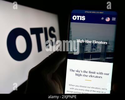 Stuttgart, Allemagne, 08-06-2023 : personne tenant un smartphone avec la page web de la société américaine d'ascenseur Otis Worldwide Corporation sur l'écran avec le logo. Mise au point Banque D'Images