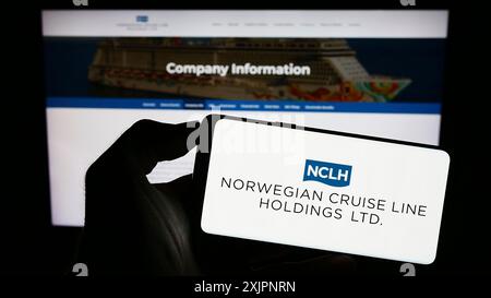 Stuttgart, Allemagne, 08-06-2023 : personne tenant un smartphone avec le logo de la société Norwegian Cruise Line Holdings Ltd sur l'écran devant le site Web. Banque D'Images