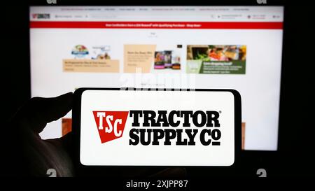 Stuttgart, Allemagne, 08-11-2023 : personne tenant un téléphone portable avec le logo de la société américaine de vente au détail Tractor Supply Company sur l'écran devant l'entreprise Banque D'Images